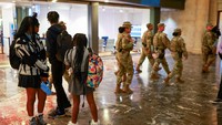 Anggota Garda Nasional AS dari Louisiana berjalan melewati pelajar saat patroli di Union Station, Washington, D.C., Senin (25/8/2025). Operasi ini memicu kekhawatiran warga di tengah musim sekolah baru. REUTERS/Jose Luis Gonzalez 