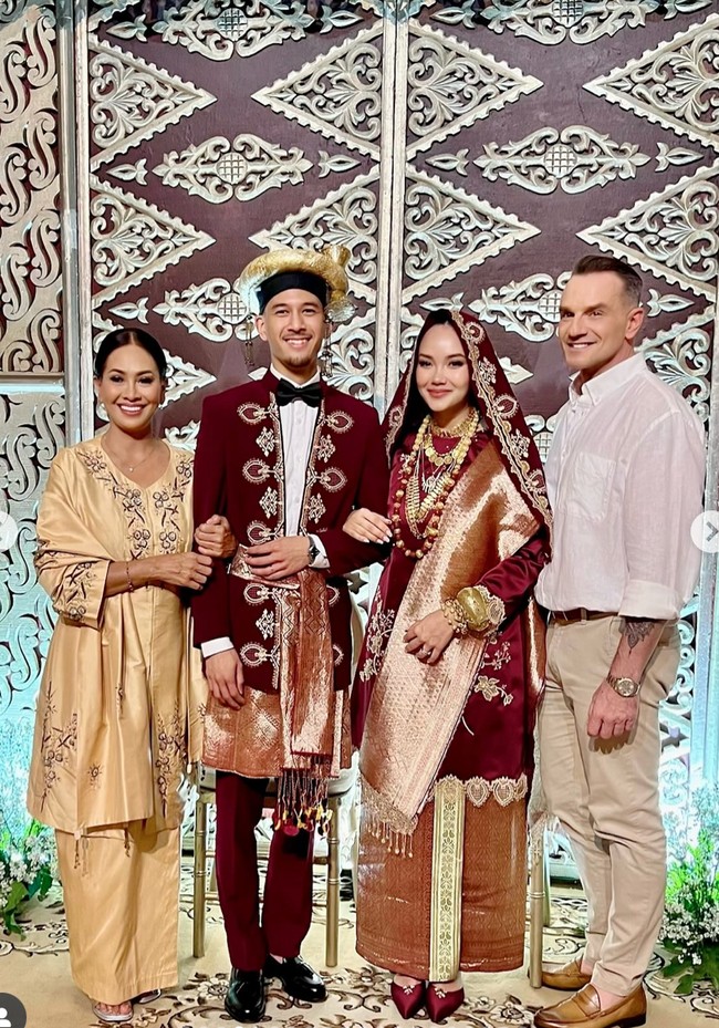 Dari foto-foto yang dibagikan di Instagram sang bunda, terlihat Alexandra dan suaminya mengenakan busana adat Koto Gadang berwarna merah marun dipadukkan dengan detail keemasan yang elegan. Foto: Instagram/@risa_dewi