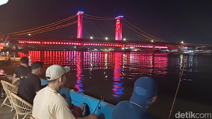 Suasana mancing berlatar Jembatan Ampera.