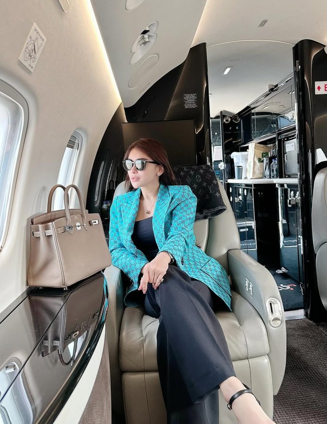 Punya gaya hidup mewah, begini gaya Bebizie saat menaiki private jet sambil membawa tas Hermes. Serba bermerek, terlihat blazer biru yang dikenakan oleh Bebizie itu berasal dari Gucci, sementara kain selimut di belakang kepalanya dari Louis Vuitton. Foto: Instagram/@bebizie