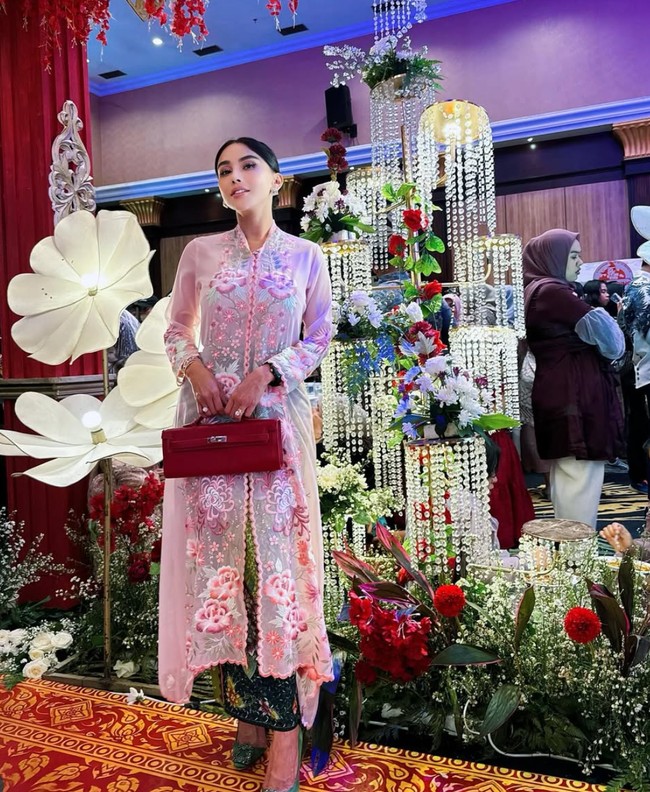 Gaya Bebizie saat kondangan dengan gaya tradisional. Ia tampak memadukan kebaya modern pink-nya dengan Hermes Kelly Cut Sanguine Swift Palladium Hardware yang ditentengnya. Diperkirakan harga clutch merah yang dibawanya itu mencapai sekitar Rp 262 juta. Foto: Instagram/@bebizie