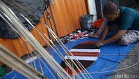 Helmi, perajin layang-layang di Pondok Aren, Tangerang Selatan, menyelesaikan pesanan di tengah penjualan yang lesu akibat kemarau basah.