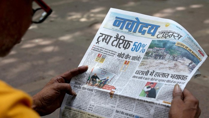 Trump Kenakan Tarif 50% ke India A man reads the latest edition of The Times of India newspaper, with the lead story on U.S. tariffs on most Indian goods, in the old quarters of Delhi, India, August 27, 2025. REUTERS/Anushree Fadnavis