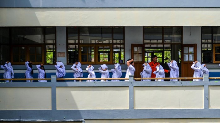 Siswa melindungi diri dengan kursi saat mengikuti simulasi penanganan gempa bumi di SMPN 1, Bandung, Jawa Barat, Kamis (28/8/2025). Pemerintah Kota Bandung melalui BPBD menggelar simulasi tanggap bencana gempa bumi yang ditujukan untuk melatih murid dalam mitigasi bencana alam secara mandiri terkait potensi gempa bumi akibat pergerakan Sesar Lembang di Kota Bandung. ANTARA FOTO/Raisan Al Farisi