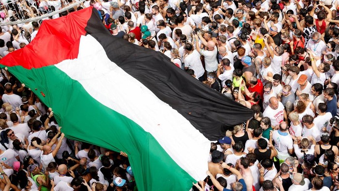 Bendera Palestina Raksasa Berkibar di Tengah Riuh Festival Tomatina Spanyol Participants carry a large Palestinian flag during the annual 'La Tomatina' food fight festival in Bunol, near Valencia, Spain, August 27, 2025. REUTERS/Eva Manez