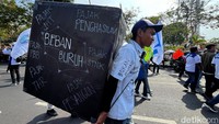 Salah satu buruh juga membawa kardus berwarna hitam dengan bertuliskan Beban Buruh dengasn berbagai turunan membayar pajak. Mulai dari pajak penghasilan, pajak STNK, pajak JHT hingga pajak PBB.