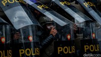Polisi tampak menggunakan tameng untuk menghindari batu dan petasan.