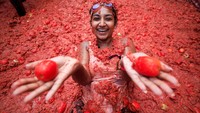 Para pengunjung bersukacita saat mereka dihujani bubur tomat dalam festival perang makanan tahunan Spanyol, Tomatina. Foto: REUTERS/Eva Manez