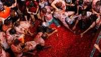 Kerumunan peserta basah kuyup tomat saling melempar dalam perang makanan terbesar di dunia, La Tomatina. Foto: REUTERS/Eva Manez