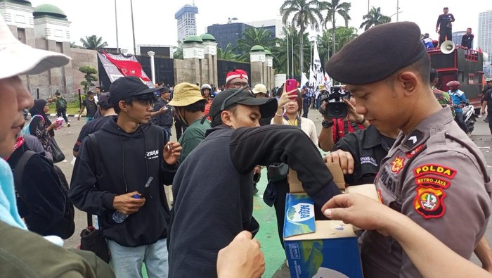 Personel Samapta Polda Metro Jaya membagikan air mineral kepada peserta demo buruh di DPR, Kamis (28/8/2025). Polisi juga membagi-bagikan roti kepada massa buruh.