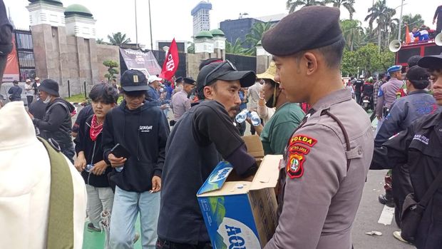 Personel Samapta Polda Metro Jaya membagikan air mineral kepada peserta demo buruh di DPR, Kamis (28/8/2025). Polisi juga membagi-bagikan roti kepada massa buruh.