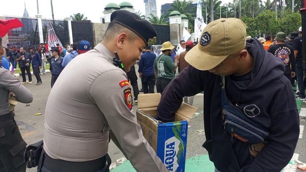 Personel Samapta Polda Metro Jaya membagikan air mineral kepada peserta demo buruh di DPR, Kamis (28/8/2025). Polisi juga membagi-bagikan roti kepada massa buruh.