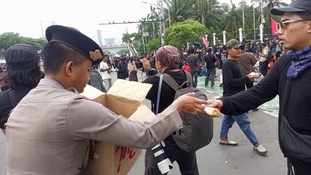 Personel Samapta Polda Metro Jaya membagikan air mineral kepada peserta demo buruh di DPR, Kamis (28/8/2025). Polisi juga membagi-bagikan roti kepada massa buruh.