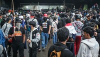 Sejumlah orang dalam kerumunan terlihat membawa bambu. Kehadiran atribut itu semakin menambah tegang suasana di titik bentrokan. 
