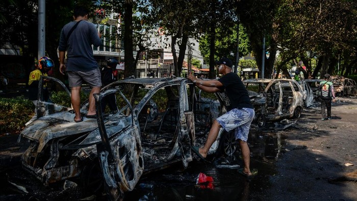 Aksi tuntut pengusutan penabrakan pengemudi ojek online Warga mengambil pintu bangkai mobil yang hangus terbakar saat aksi menuntut pengusutan kasus penabrakan pengemudi ojek online oleh mobil rantis Brimob di Kwitang, Jakarta, Jumat (29/8/2025). ANTARA FOTO/Putra M. Akbar/nz