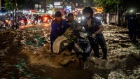 Petugas berupaya mengatur arus lalu lintas hingga motor yang terjebak arus saat banjir luapan Kali Baru membuat jalur utama Jakarta-Bogor tersendat. Foto: ANTARA FOTO/Bayu Pratama S