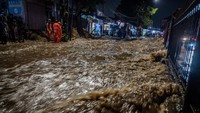 Air bercampur lumpur meluber ke jalan raya setelah dinding bangunan di tepi Kali Baru tidak mampu menahan derasnya arus. Foto: ANTARA FOTO/Bayu Pratama S