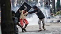 Polisi mendorong mundur massa dengan menggunakan tembakan gas air mata. Massa yang semula berada tepat di depan Markas Brimob langsung berhamburan.