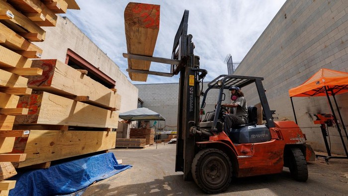 A drone view shows Jeff Perry, founder of Angel City Lumber, as he drives away in his mechanized tractor to collect trees lost to the Eaton Fire, in Altadena, California, U.S., August 21, 2025. Perry is helping residents rebuild their homes with wood from trees damaged in the fire.  REUTERS/Mike Blake