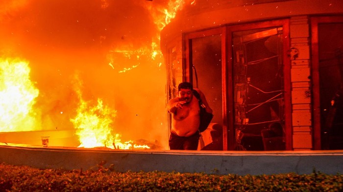 Seorang pengemudi ojek online mengambil gambar Mess MPR RI yang dibakar di Bandung, Jawa Barat, Jumat (29/8/2025). Mess MPR RI dibakar oleh massa aksi yang menuntut pembatalan kenaikan tunjangan Anggota DPR RI serta pengusutan penabrakan pengemudi ojek online. ANTARA FOTO/Raisan Al Farisi/rwa.