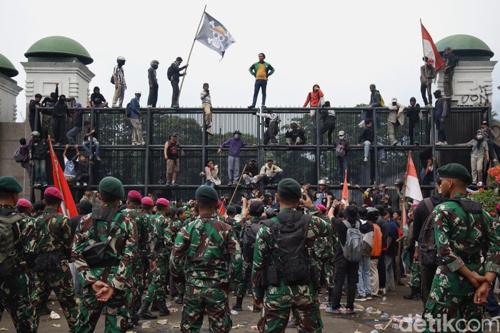 Massa sempat menembus gerbang DPR RI dengan mencopot besi pagar, Jumat (29/8/2025). Sebagian massa yang berhasil masuk ditenangkan anggota TNI dan secara persuasif  meminta para pendemo untuk kembali ke luar pagar. Polisi mundur dan berjarak sekitar 30 meter dari aparat TNI yang berjaga.