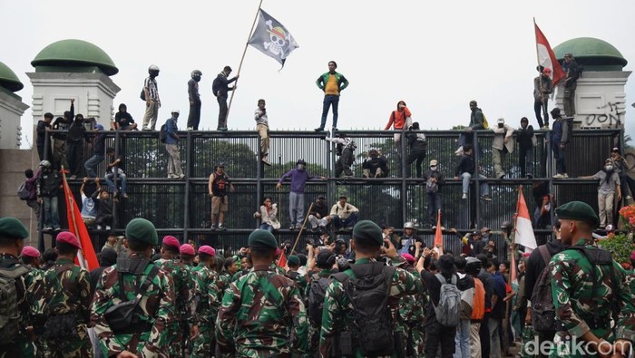 Massa sempat menembus gerbang DPR RI dengan mencopot besi pagar, Jumat (29/8/2025). Sebagian massa yang berhasil masuk ditenangkan anggota TNI dan secara persuasif  meminta para pendemo untuk kembali ke luar pagar. Polisi mundur dan berjarak sekitar 30 meter dari aparat TNI yang berjaga.