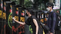 Massa mencoret tameng yang dipakai personel polisi.