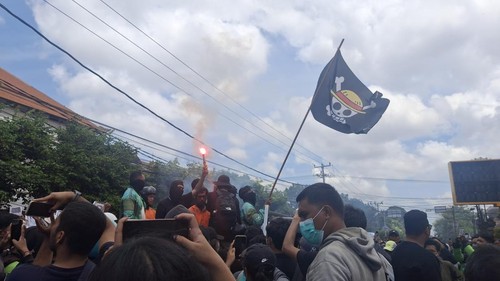 Bendera One Piece Jolly Joger berkibar sebagai simbol perlawanan dalam demonstrasi di Mapolda Bali, Sabtu (30/8/2025). (Fabiola Dianira/detikBali)