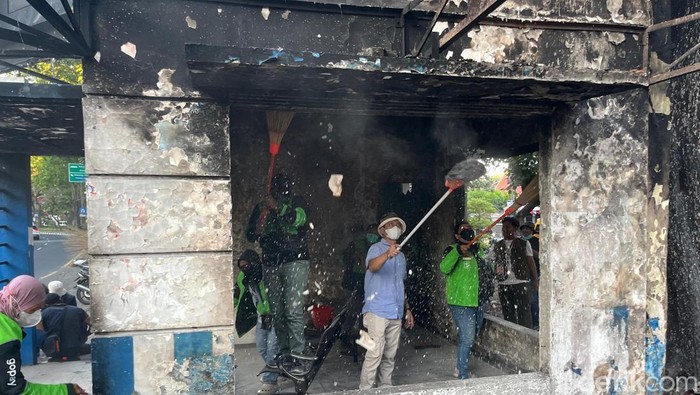 Ojol dan warga bersihkan pos polisi yang sempat dibakar di Surabaya