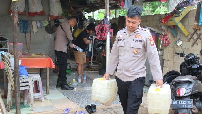 Polisi membawa barang bukti arak.