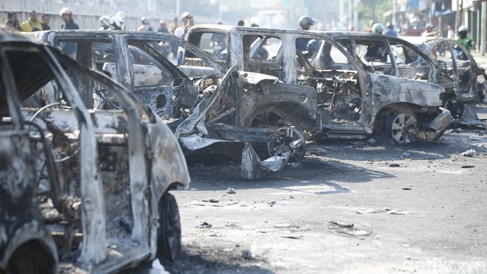 Pengepul besi mengambil bagian mobil yang terbakar di Jalan Matraman Raya, Jakarta, Sabtu (30/8/2025).