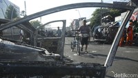 Warga menyaksikan bangkai mobil terbakar yang berserakan di sisi jalan usai kerusuhan.