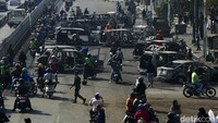 Sejumlah pengendara motor melintas di antara mobil-mobil yang hangus terbakar di Jalan Matraman Raya, Jakarta, Sabtu (30/8/2025).