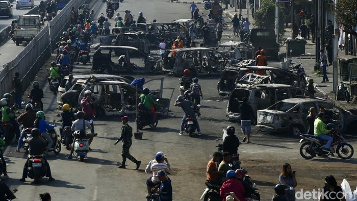 Potret 12 Puing Mobil yang Terbakar Semalam di Matraman Pengepul besi mengambil bagian mobil yang terbakar di Jalan Matraman Raya, Jakarta, Sabtu (30/8/2025).