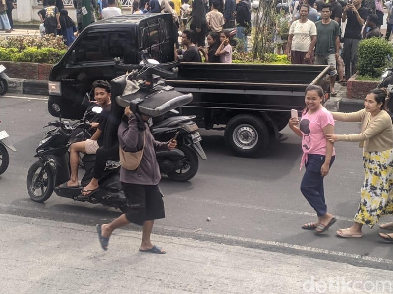 Seorang pendemo terlihat memikul kursi kantor yang diambil dari Gedung DPRD NTB