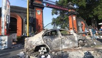 Warga mengamati mobil yang terbakar pascakerusuhan di depan gedung Pemkab Kediri, Jawa Timur, Minggu (31/8/2025). Polisi masih menyelidiki kelompok pelaku yang diduga memicu aksi anarkis tersebut. ANTARA FOTO/Prasetia Fauzani