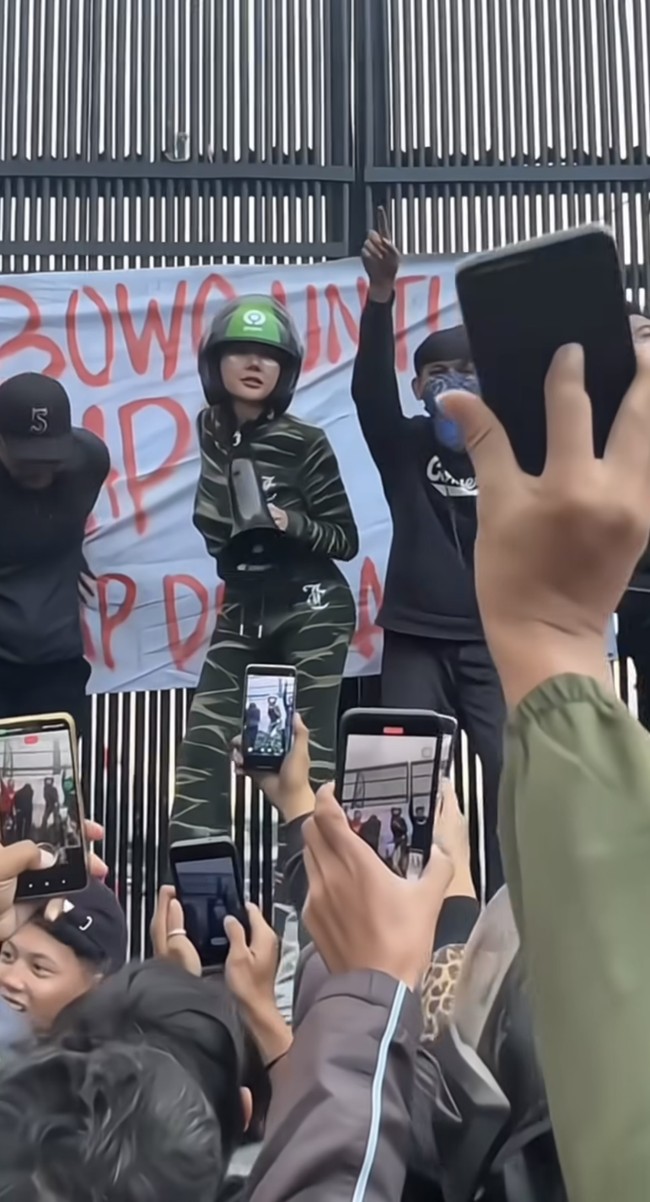 Tak mau ketinggalan, Lucinta Luna juga turut menyambangi halaman gedung DPR. Ia tampak mengenakan setelan hijau loreng-loreng. Melengkapi penampilannya Lucinta juga mengenakan helm hitam-hijau khas salah satu transportasi online. Foto: Instagram/@lucintaluna_manjalita