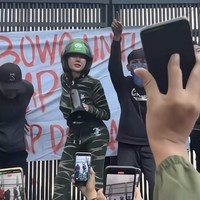 Tak mau ketinggalan, Lucinta Luna juga turut menyambangi halaman gedung DPR. Ia tampak mengenakan setelan hijau loreng-loreng. Melengkapi penampilannya Lucinta juga mengenakan helm hitam-hijau khas salah satu transportasi online. Foto: Instagram/@lucintaluna_manjalita