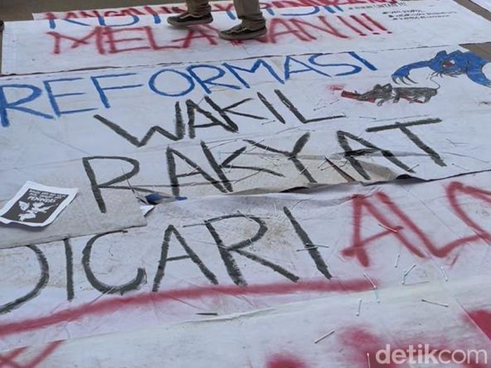 Mahasiswa menaburkan cotton bud di atas spanduk aksi di depan DPRD Kalbar.