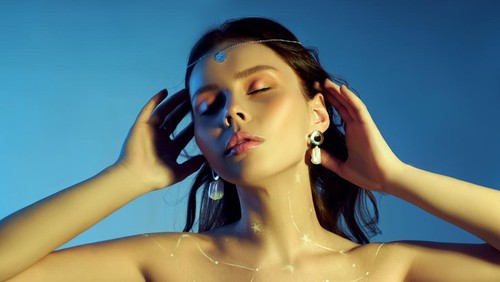 Beauty portrait of a woman with beautiful makeup, earrings and a necklace on the girl. Drawing Cosmos constellation of the zodiac on a woman chest