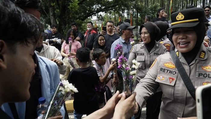 Polwan Polda Riau membagikan bunga kepada mahasiswa pendemo di momen HUT ke-77, Senin (1/9/2025).