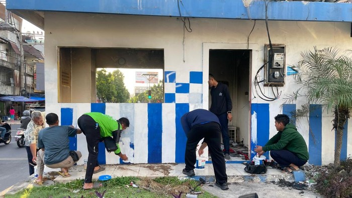 Driver ojol dan warga secara swadaya memperbaiki pos polisi yang dibakar saat kerusuhan di Surabaya.
