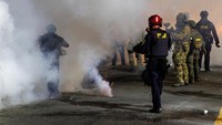 Aksi yang awalnya berlangsung damai berubah ricuh ketika petugas keamanan federal menembakkan gas air mata untuk membubarkan massa. Asap pekat mengepul di sekitar area, membuat demonstran berlarian mencari perlindungan. REUTERS/John Rudoff