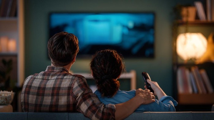 Happy family watching TV, movies in the evening at home. Couple spending time together.