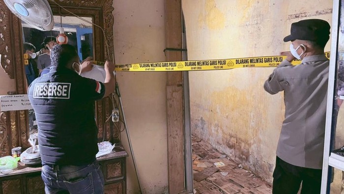 Polisi memasang garis polisi tempat ditemukannya pemilik salon tewas membusuk di kamarnya.
