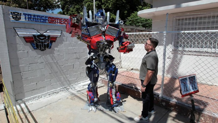 Pengrajin Venezuela Ciptakan Patung Kreatif untuk Promosikan Daur Ulang Artist Yhorby Ventura stands with a sculpture in the style of a character from Transformers that he made from recycled materials, at his house in Maracaibo, Venezuela, August 28, 2025. REUTERS/Isaac Urrutia