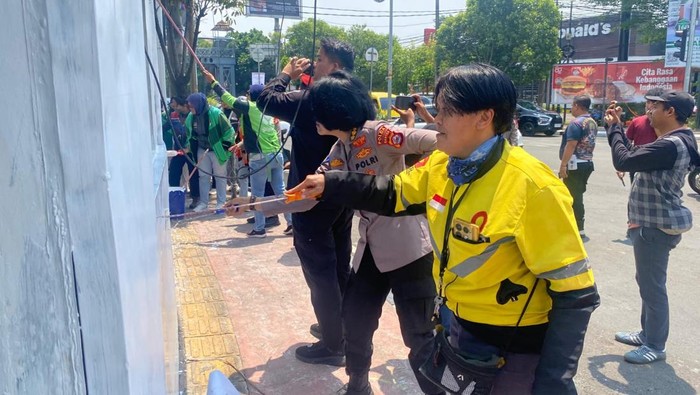 Polisi dan pengendara ojek online (ojol) membersihkan Pospol Lantas Ciceri, Kota Serang. Pospol tersebut sebelumnya rusak dan terbakar imbas kericuhan. (Dok istimewa).