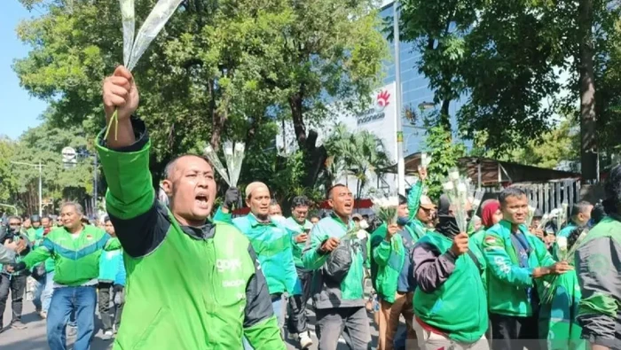 Sejumlah driver ojol menggelar aksi damai membagikan mawar kepada pengguna jalan dan anggota TNI-Polri di area Monas sebagai tanda perdamaian. (ANTARA/Khaerul Izan)