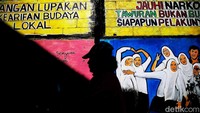 Warga melintasi mural yang sarat pesan sosial, dari kritik hingga harapan akan kehidupan kota yang lebih baik.