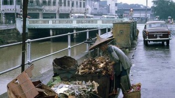Foto warna ini diambil pada sekitar tahun 1960-an di Singapura. Menggambarkan seperti apa situasi di sana kala itu. Tampak suasananya dan warganya masih sederhana.Seorang lansia tampak mengais sampah di salah satu sudut negara itu  Foto: Vintages